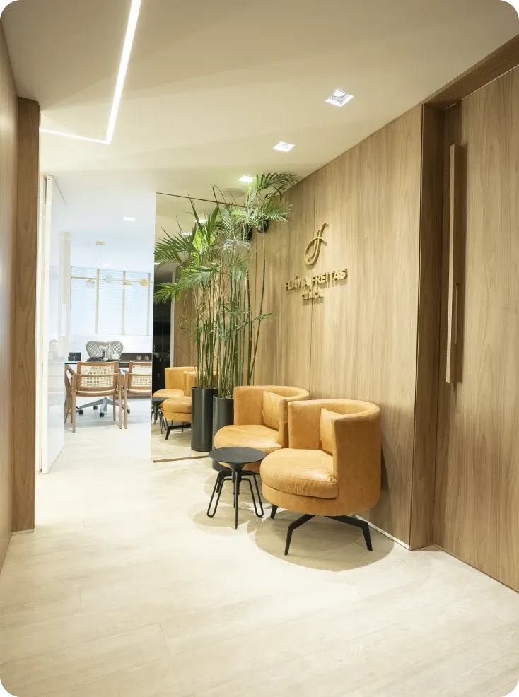 Recepção da Clínica Flávia Freitas com poltronas caramelo e o logotipo na parede de madeira